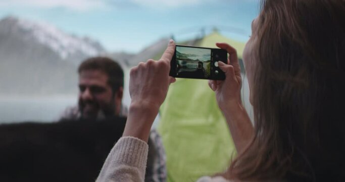 Caucasian female taking photos of her boyfriend playing with dog on a campsite. Shot on RED Dragon cinema camera