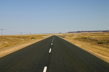 Fototapeta na wymiar A long paved road stretches to a distant horizon