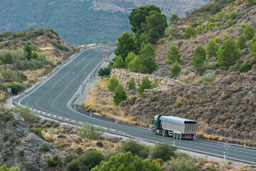 Tipper truck driving on a secondary road and uphill.
