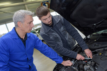 Fototapeta na wymiar student with instructor repairing a car during apprenticeship