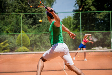 Young athletic couple playing tennis on the court.