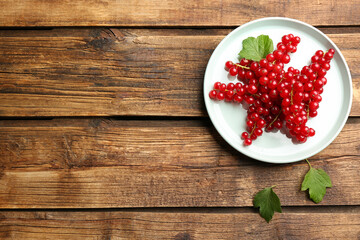 Delicious ripe red currants on wooden table, flat lay. Space for text