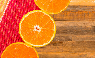 Laranjas cortadas e fundo de tecido colorido e madeira rústica
