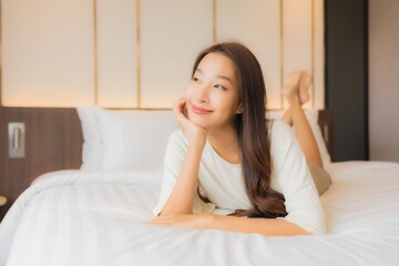 Portrait beautiful young asian woman smile relax on bed in bedroom interior