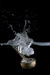 
Tibetan bowl dipping into water, on black background