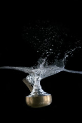 
Tibetan bowl dipping into water, on black background