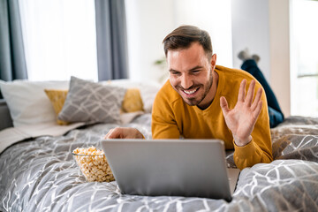 Happy young man video chatting on laptop computer at home