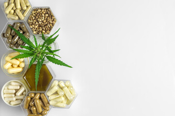 Cannabis medicine capsules, hemp oil and seeds and green plant in honeycomb jars