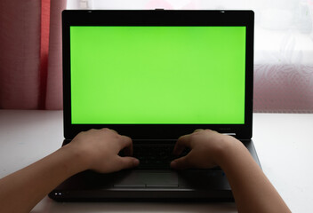 Laptop with green screen. With fingers on the keyboard. Gaming. Playing. Location - Limbazi, Limbazu novads, Latvia. Shoot date - 10/04/2020.