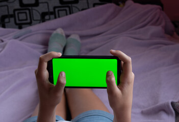 Phone with green screen, horizontal. With fingers on the screen. Gaming. Location - Limbazi, Limbazu novads, Latvia. Shoot date - 10/04/2020.