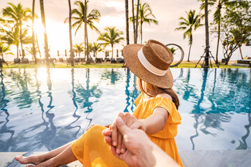 Young couple traveler relaxing and enjoying the sunset by a tropical resort pool while traveling...