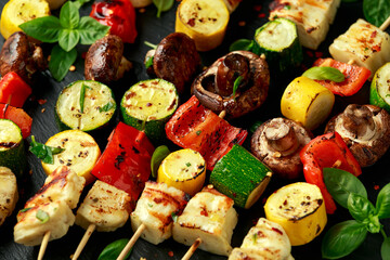 Grilled Halloumi cheese skewers with vegetables on rustic stone board