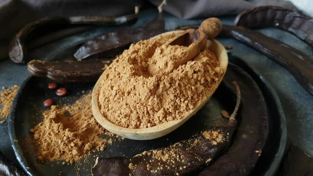 Dry carob pods and powder close up