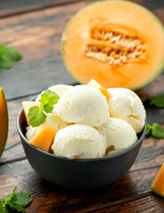 Melon ice cream with mint in bowl on wooden table