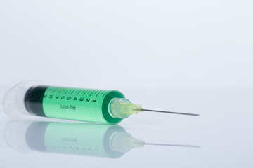 filled syringe mirrored on white ground, horizontal alignment