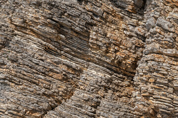 Closeup photo of pancake sedimentary rock formations on the coast.  Water pressure caused dead marine creatures and plants landed on the seabed about 2 km below the surface.to solidify into layers.