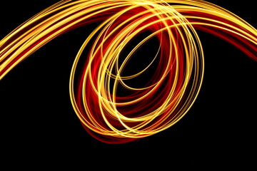 Long exposure photograph of neon red and gold colour in an abstract swirl, parallel lines pattern against a black background. Light painting photography.