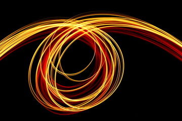 Long exposure photograph of neon red and gold colour in an abstract swirl, parallel lines pattern against a black background. Light painting photography.