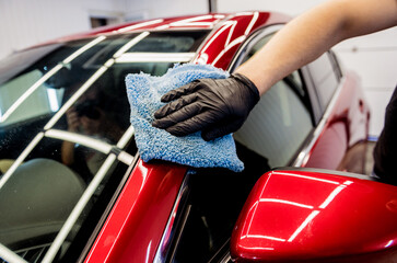 Car service worker polishing car with microfiber cloth.