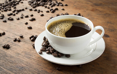 cup of coffee with beans on wooden table