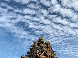 Wooden orthodox church domes in the blue sky with clouds