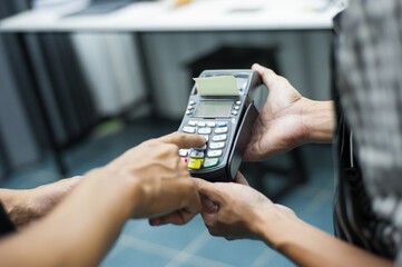 Waiter holds the card machine while the customer is dialing the code on the card reader to pay.