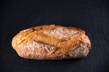 Rustic bread, beautiful golden crust with diamond patterns, top view, on black background	
