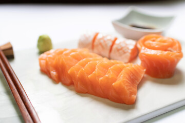 Fresh salmon and toro sashimi with shoyu and wasabi with chopsticks on mable plate. 