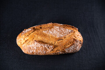 Rustic bread, beautiful golden crust with diamond patterns, top view, on black background	