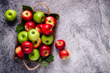 Ripe red and green apples in wooden box.