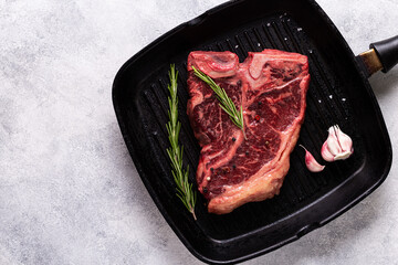 Fresh raw t-bone steak on frying grill pan.