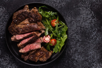 Grilled beef steak with spices on a black plate