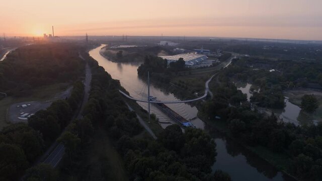 Rhine-Herne Canal With A Barge Passing Under The Grimberger Sichel Bridge At Sunset In Gelsenkirchen, Germany. - aerial pullback shot