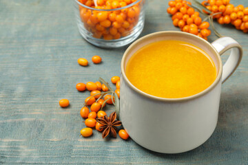 Fresh sea buckthorn tea on blue wooden table