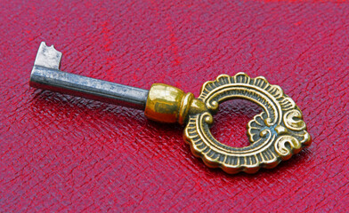 Decorative Antique Brass Key on red leather background. 