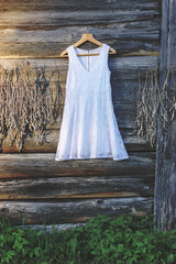 Linen white dress hanging on a hanger outdoors