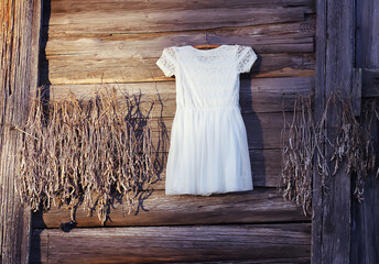 Linen white dress hanging on a hanger outdoors