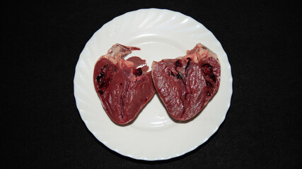Pork heart arranged in a white plate, on a black background