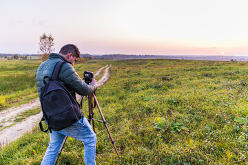 Fototapeta premium Photographer traveler adjusts the camera lifestyle professional activity hiker landscape