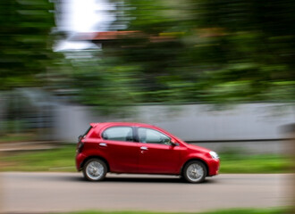 Fototapeta na wymiar red car in motion with blurred background