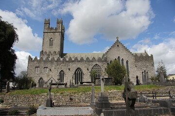 Fototapeta na wymiar Stone church with cemetery next door and some greenery in Limerick