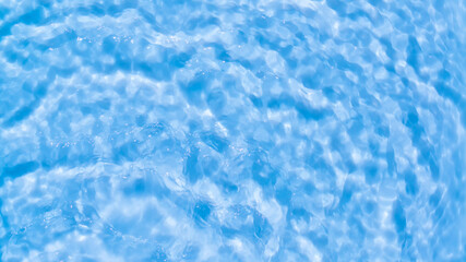 Fototapeta na wymiar Photo of water waves shadow on pool bottom. Subtle texture of light-shadow pattern of sunlight reflection from fresh rippled water surface. Beautiful natural wallpaper. Blue water waves marbling