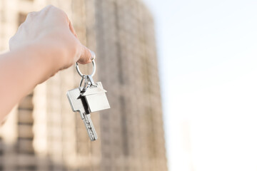 Key with house keychain in hand on construction site background