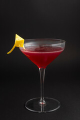 Cosmopolitan cocktail in nice red color in front of a black background.