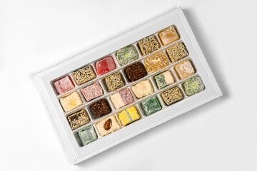 Turkish Delight or lokum, many colorful sweet cubes in cardboard box, on white background. Eastern traditional dessert. Copy space.