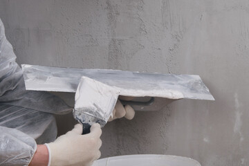 against the background of a concrete wall, a large tool for applying putty to the tool for leveling the wall, there is a place for the inscription