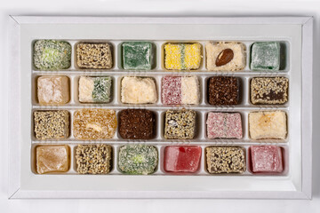 Turkish Delight or lokum, many colorful sweet cubes in cardboard box, on white background. Eastern traditional dessert. Copy space.