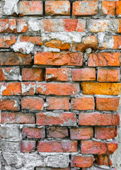 Naklejka premium The texture of an old, destroyed wall and a building made of red, orange uneven bricks with cracks, gray cement and concrete. Photography, abstraction, background.