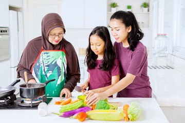 Elderly woman teach her grandchild to cut vegetable