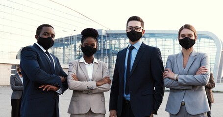 Portrait of mixed-races businessmen and businesswomen in masks and official style standing in urban city and looking at camera. Multi ethnic males and females business partners Men an women colleagues